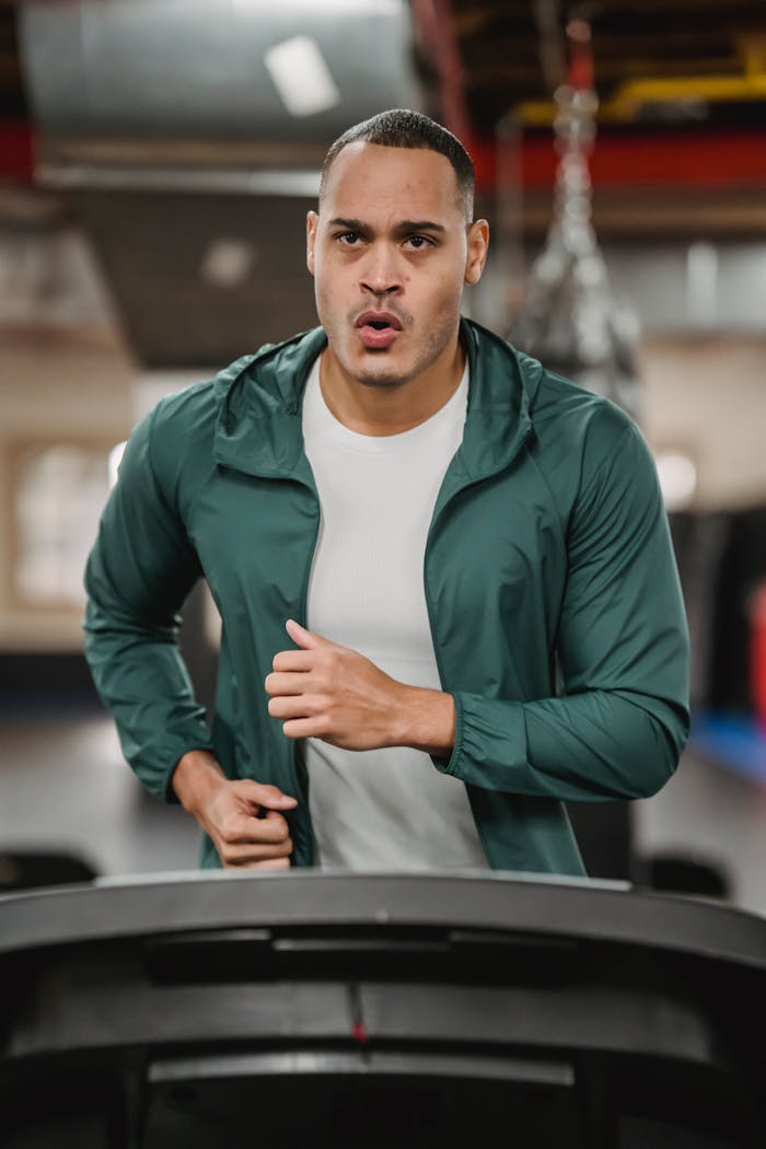 A determined man running on a treadmill in a gym setting, showcasing fitness and motivation.